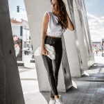 woman in the city in black pants and white top with white bag
